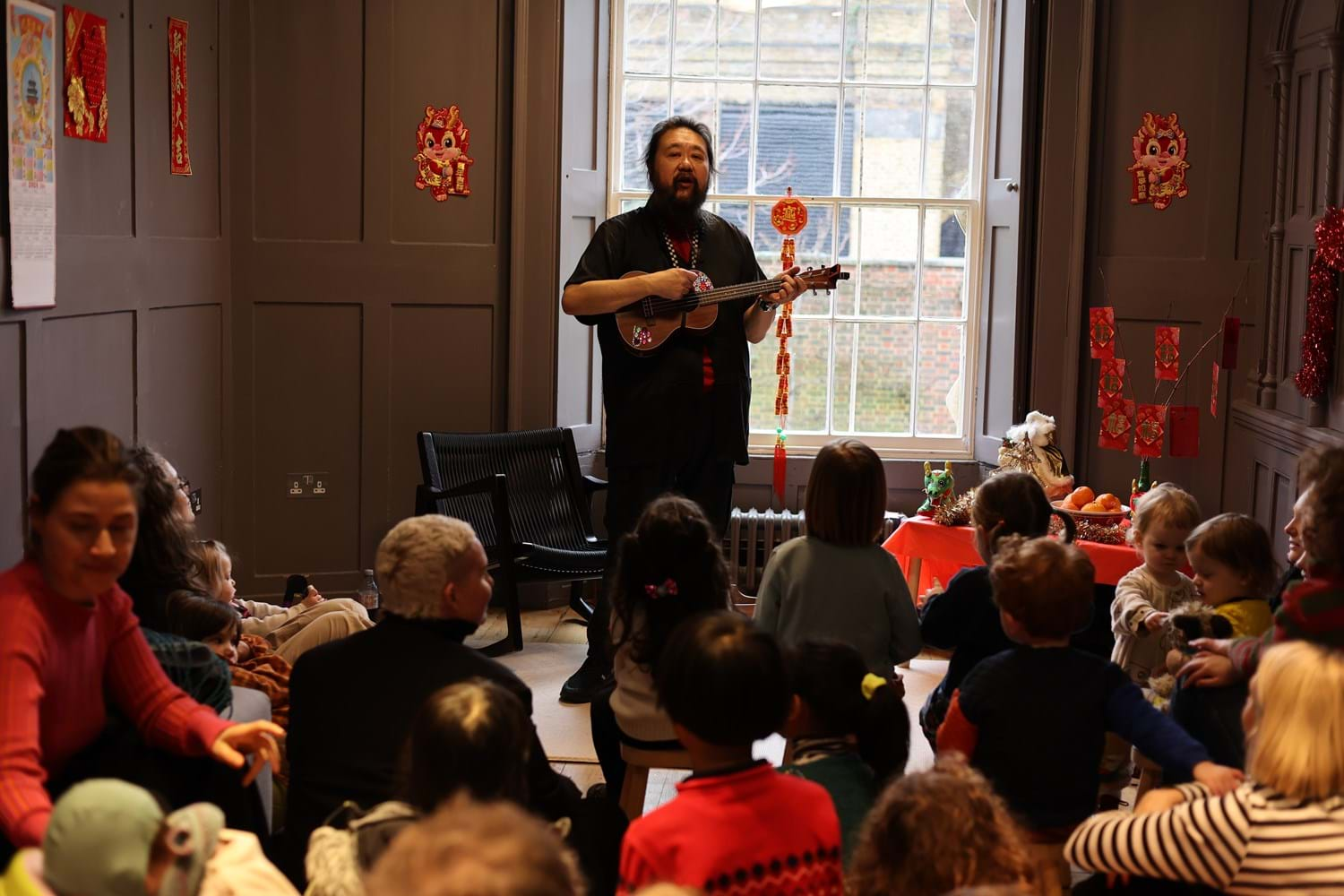 A storyteller with a musical instrument is sharing stories in front of children.