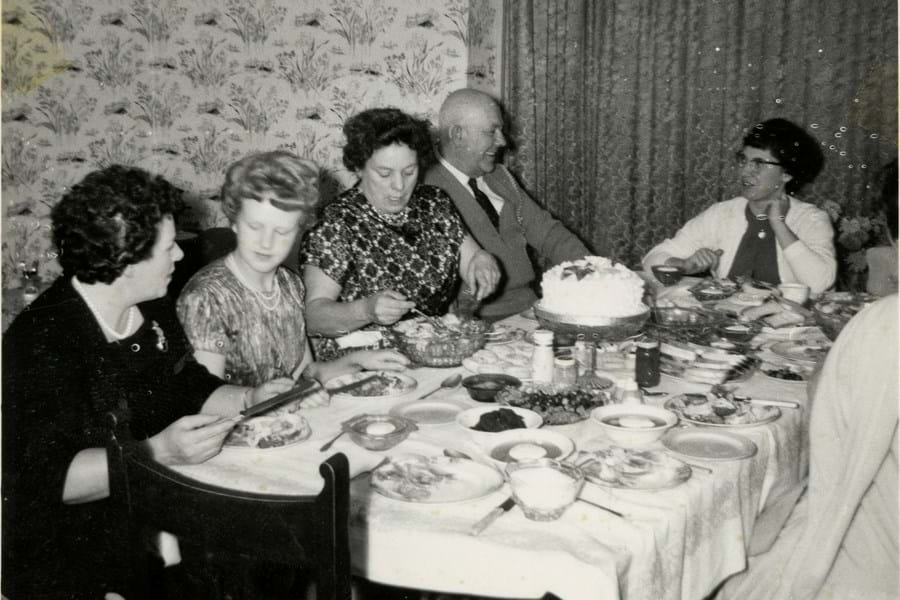 Black and white photo of a group of adults eating at a dinner table