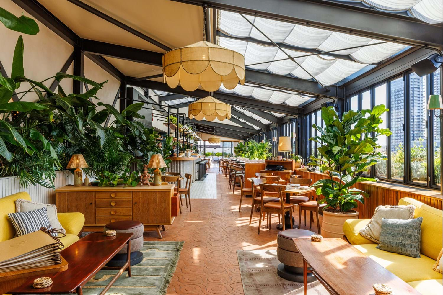 Rooftop lounge overlooking London with yellow sofas and wooden tables