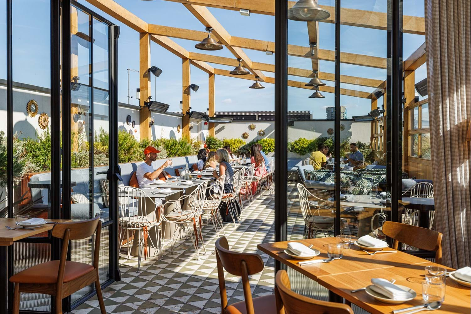 A rooftop bar with people dining in the sun