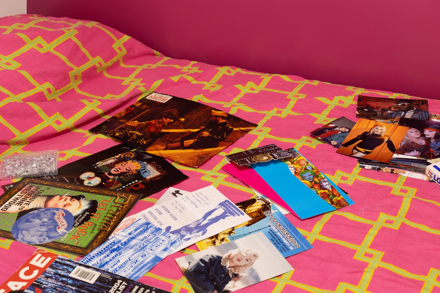 Noughties memorabilia strewn on a bed with hot pink bedding and walls