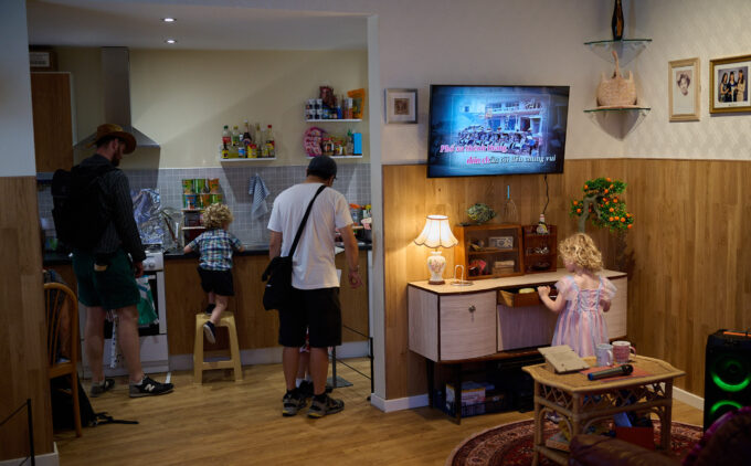 Visitors exploring a recreated home interior, with adults and children examining the kitchen and living room display.