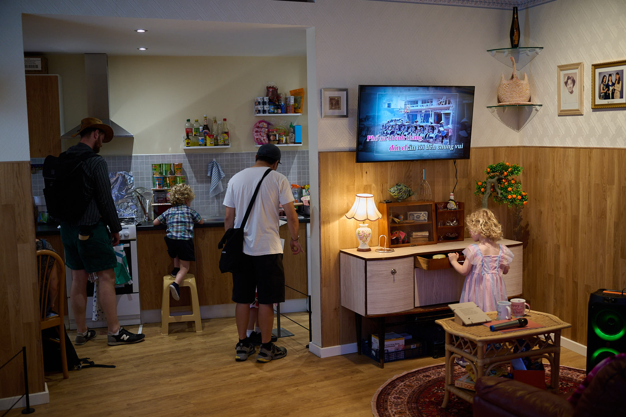 Visitors exploring a recreated home interior, with adults and children examining the kitchen and living room display.