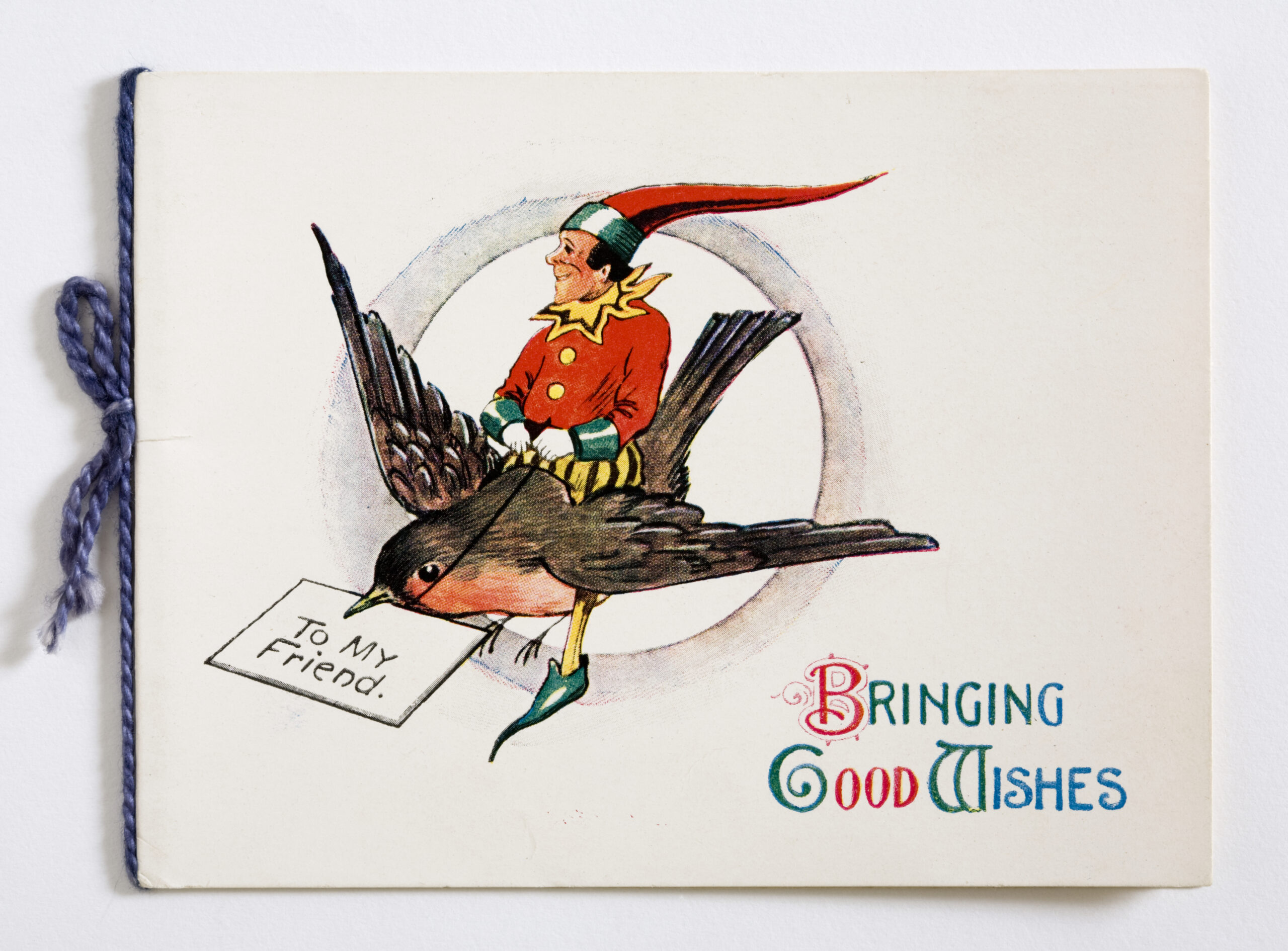 Christmas card printed with a design of an elf riding a robin with a letter inscribed 'To My Friend' in its beak, with a paper insert secured with blue cotton thread