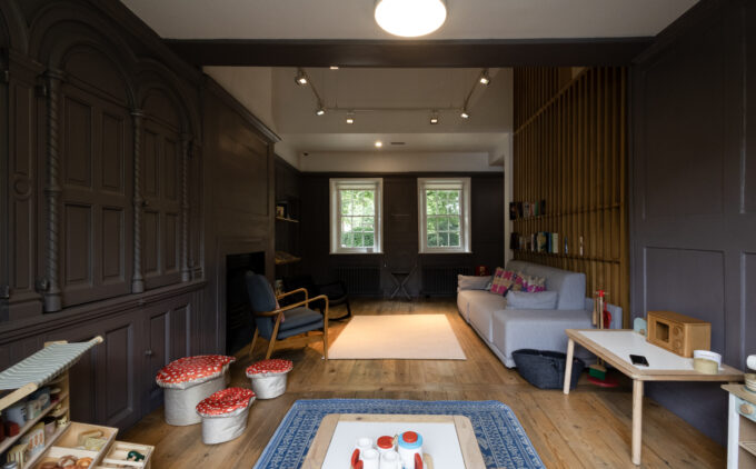 Family area in the museum with wooden floors, a sofa, and wooden kitchen set up for children