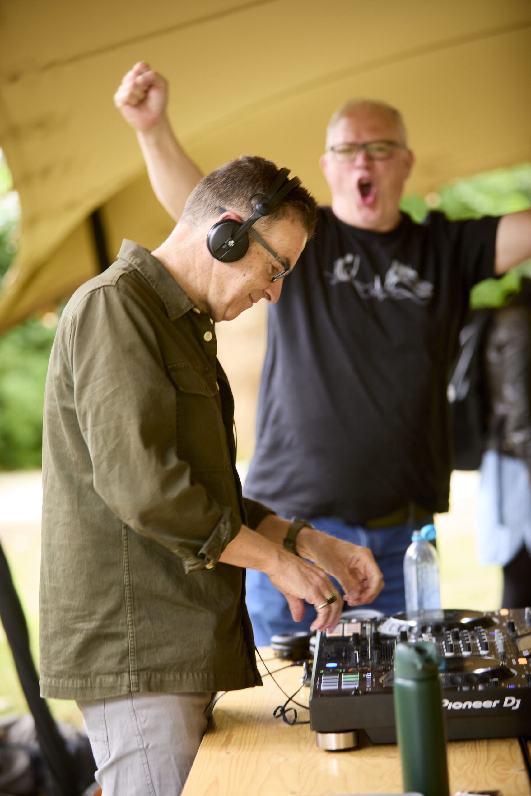 A man cheers behind a DJ