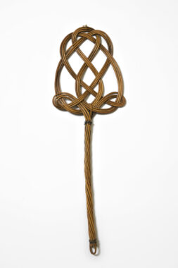 Woven rattan carpet beater with intricate braided pattern and long handle