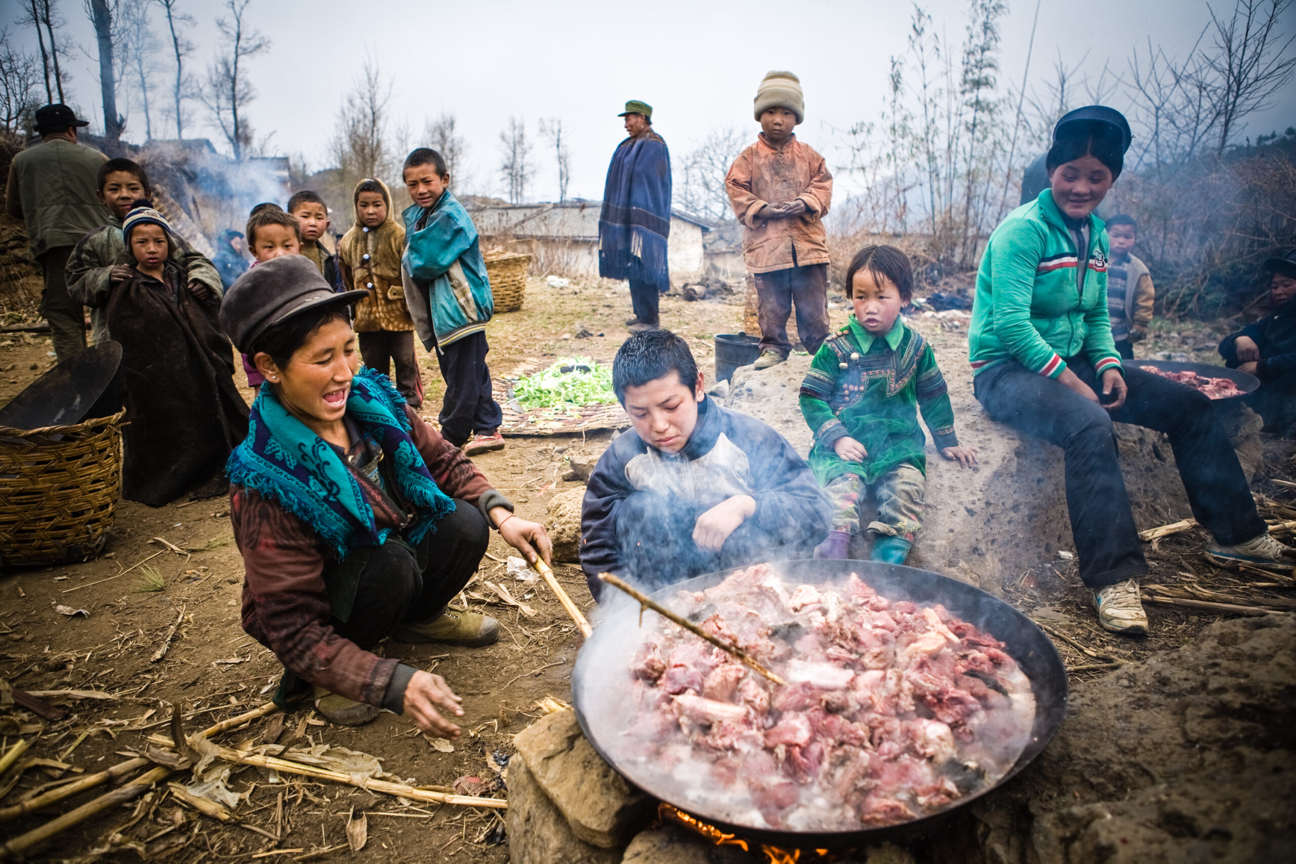 A family gather around a large pot of meat smiling