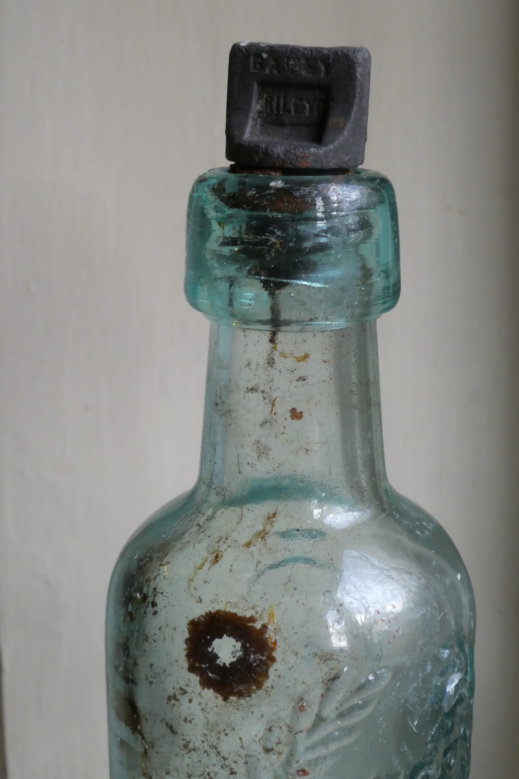 Light blue glass bottle with stopper, showing weathering and residue.