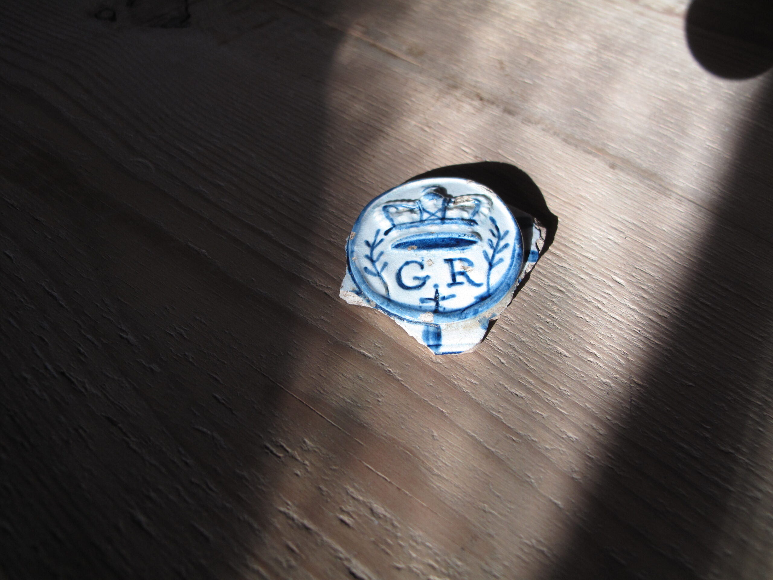 Blue and white ceramic fragment with crown design and 'G.R' initials.