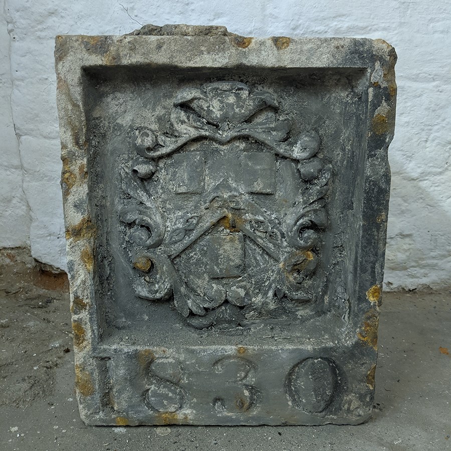 Carved stone with decorative coat of arms and the date '1830'.