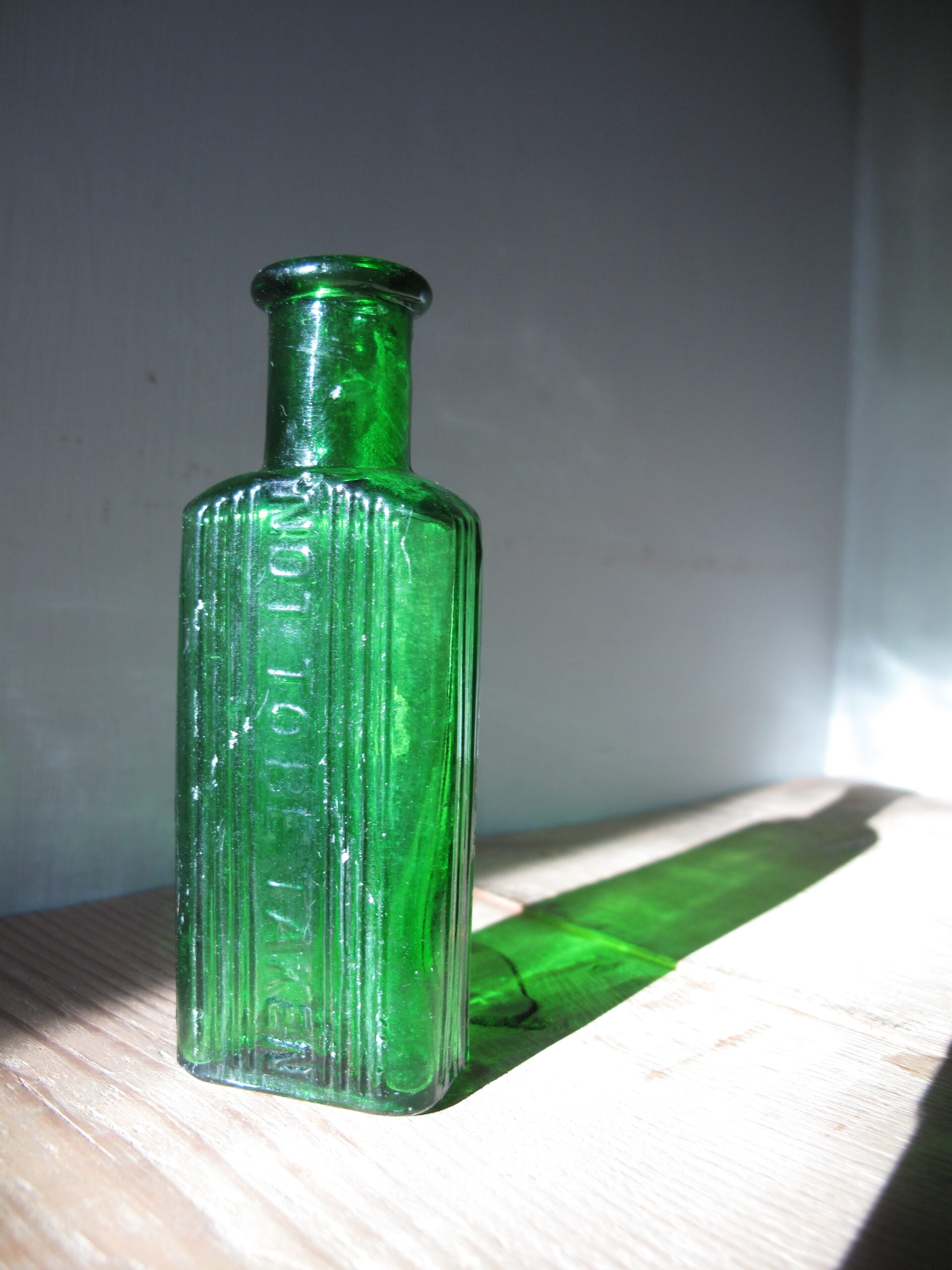 Green glass bottle with embossed text.