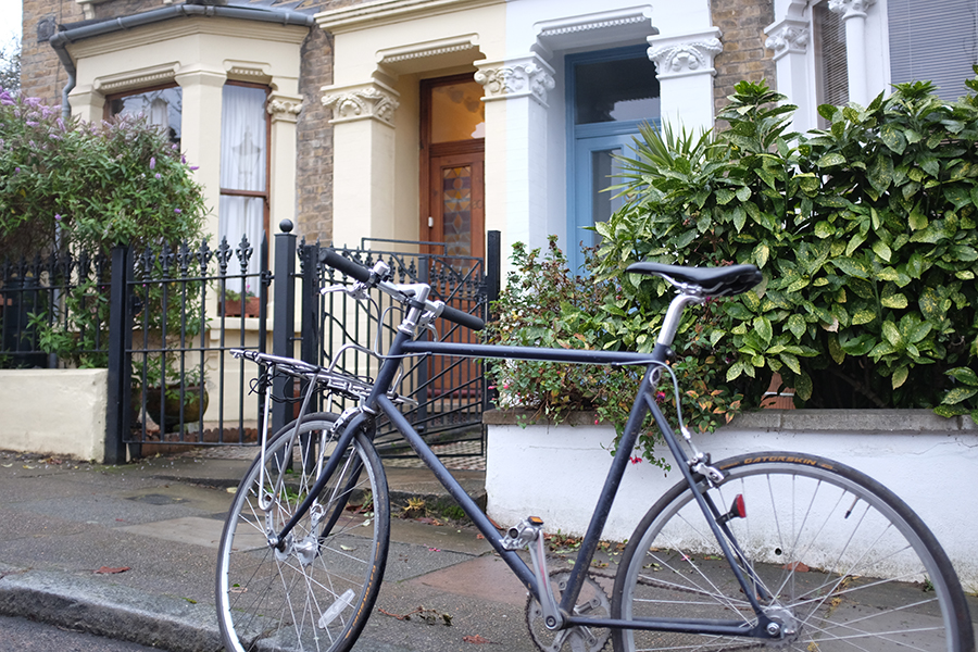 A bicycle leans in front of the facade of two houses.