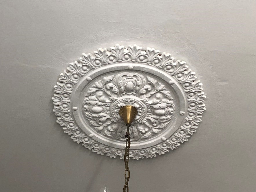 Ornate white plaster ceiling rose with decorative molding.