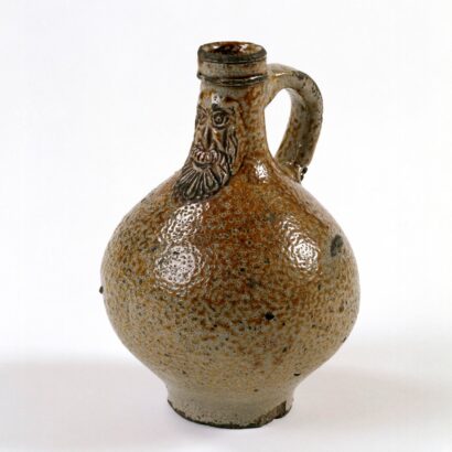 Stoneware jug with bearded face decoration, round body, spotted brown glaze and single handle.