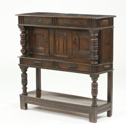 Oak court cupboard with carved panels, turned columns, and multiple drawers on tall legs with lower shelf.