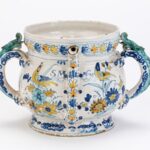 Ceramic posset cup with blue and yellow floral decoration and green lizard handles.
