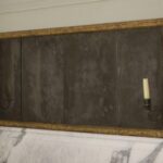 Gilt-framed horizontal mirror with candle sconces mounted on a marble surface.