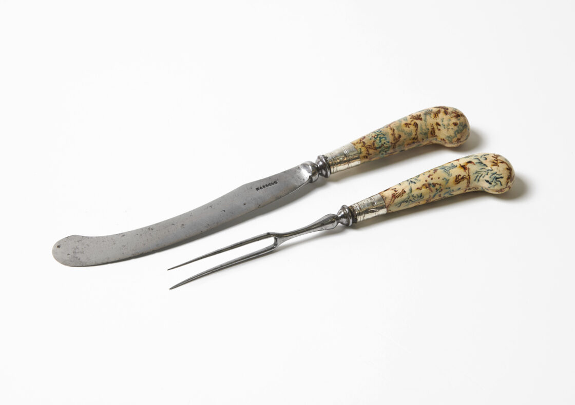 A curved knife and two-pronged fork with decorative, patterned handles.