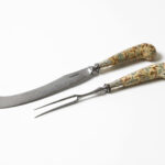 A curved knife and two-pronged fork with decorative, patterned handles.
