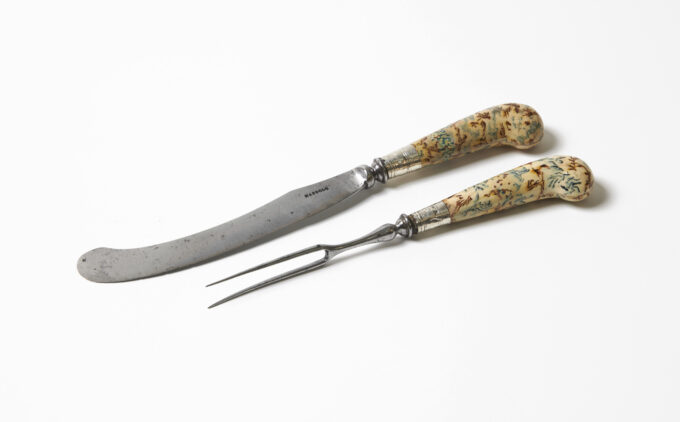 A curved knife and two-pronged fork with decorative, patterned handles.