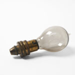 Antique light bulb with a worn brass base and a slightly smoky glass globe.