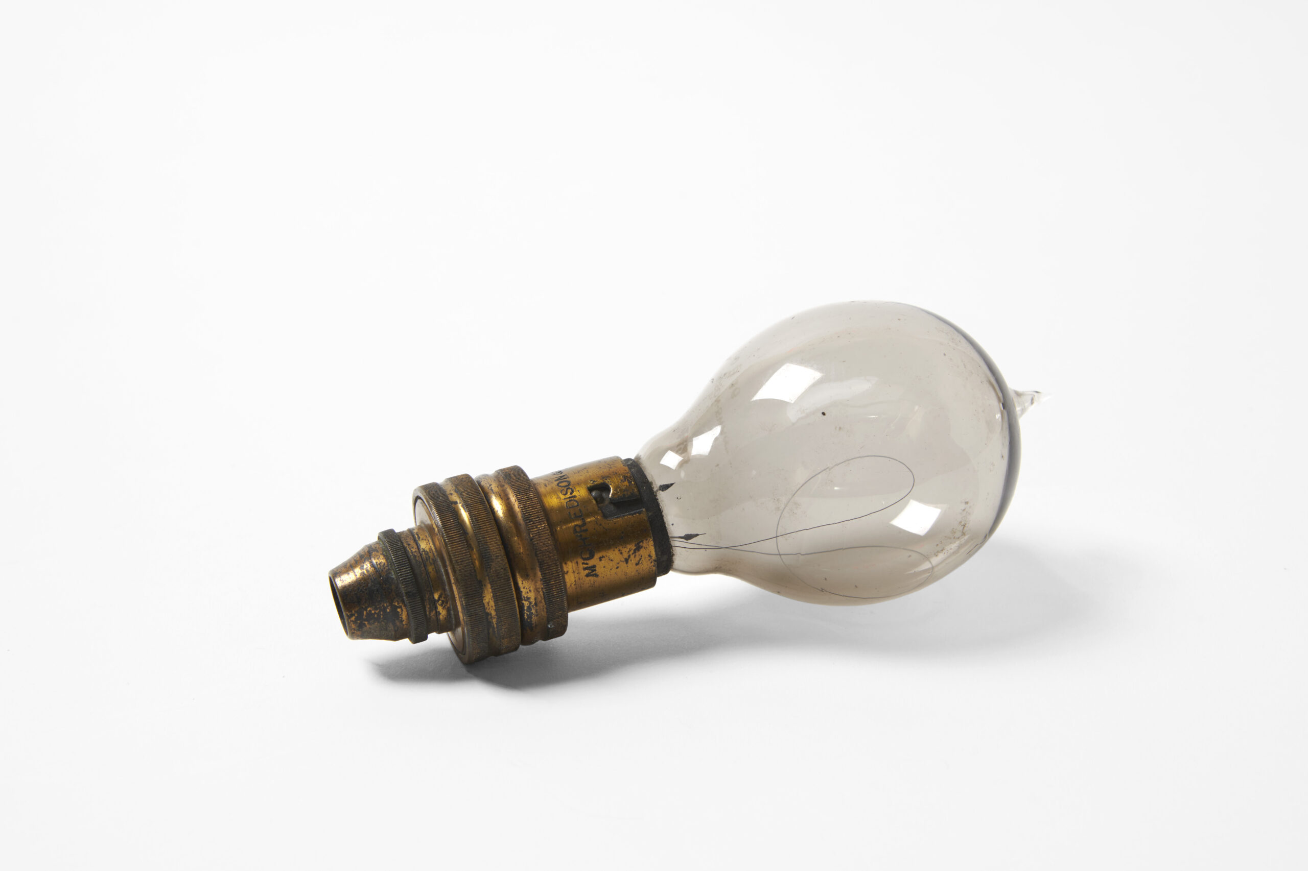 Antique light bulb with a worn brass base and a slightly smoky glass globe.