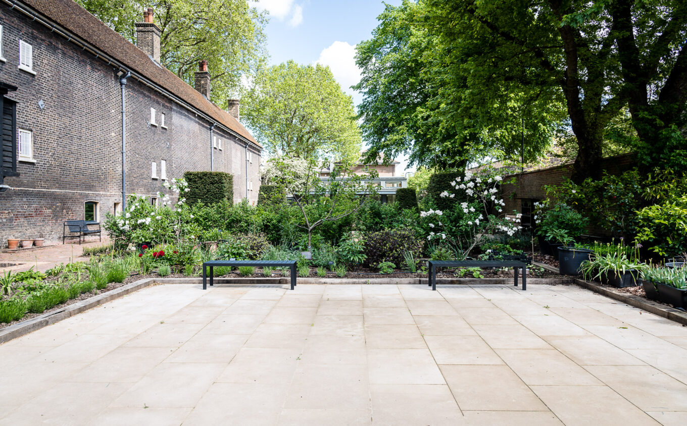 An empty terraced garden with two benches surrounded by trees