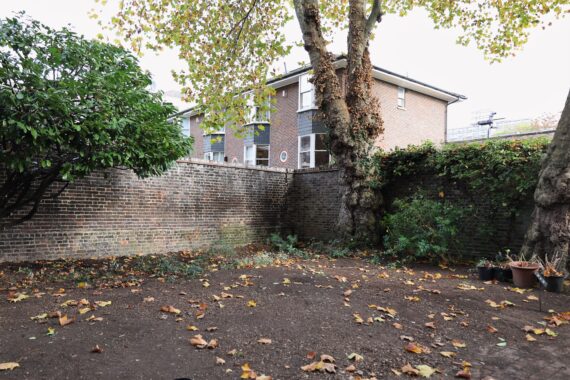 An empty garden plot with soil and brick walls at the back