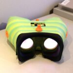 Green and yellow VR headset with orange accents positioned for viewing into the device.