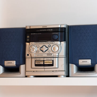 Two blue and grey speakers flank a grey CD player, which features various buttons and knobs.