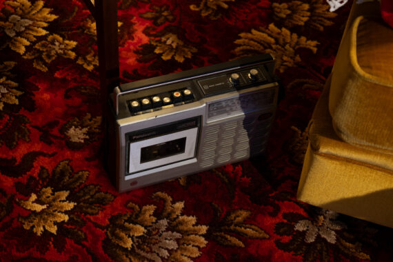 A cassette player and radio with silver and black design sitting on a decorative floral carpet
