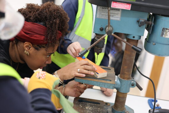 A person focusing on drilling a hole in wood for a children's workshop
