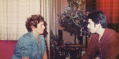 Two people having a conversation in living room with Christmas tree in background