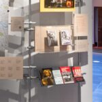 A display in a gallery with a glass case and book stands with squatters' handbooks inside.