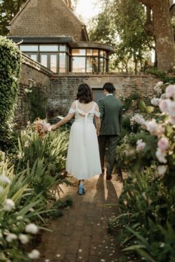 A couple getting married walk together through a garden path with roses
