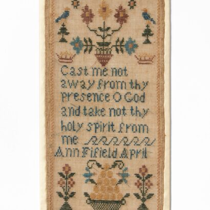 Rectangular embroidered sampler on beige fabric, featuring a central cross-stitched prayer: “Cast me not away from thy presence O God and take not thy holy spirit from me. Ann Fifield April". Above the text are four flowers in symmetry sided by blue birds and small trees; below are two flowering urns and a basket full of fruit.