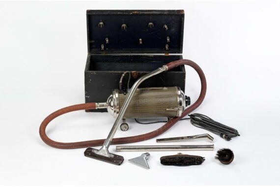 vacuum cleaner with metal canister, brown hose, and various attachments in black storage case