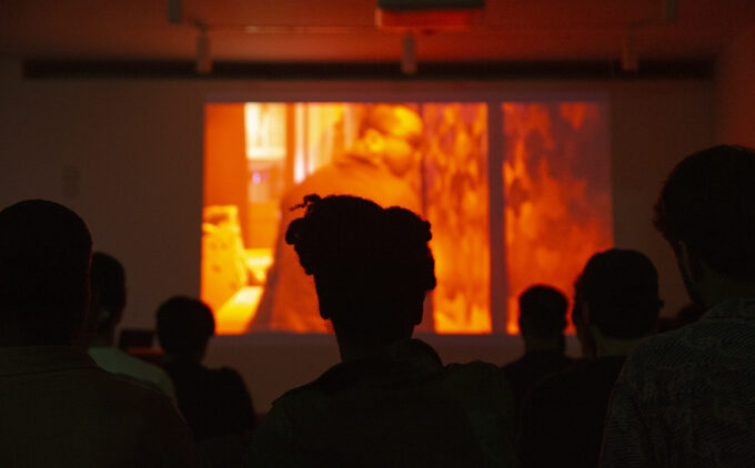 People's silhouettes watching a film screening projected