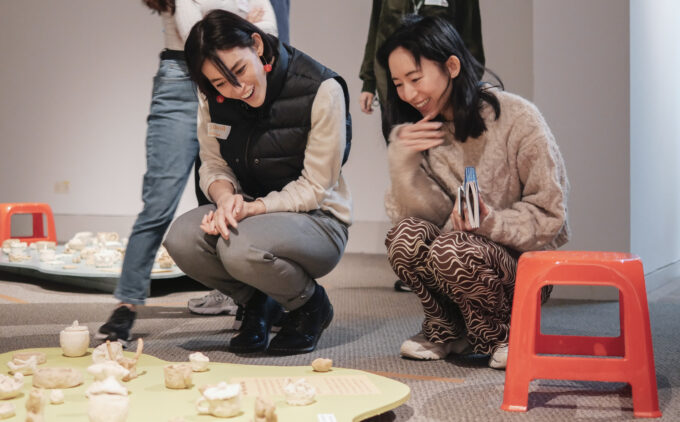 Two people sitting on the floor, smiling at an art display