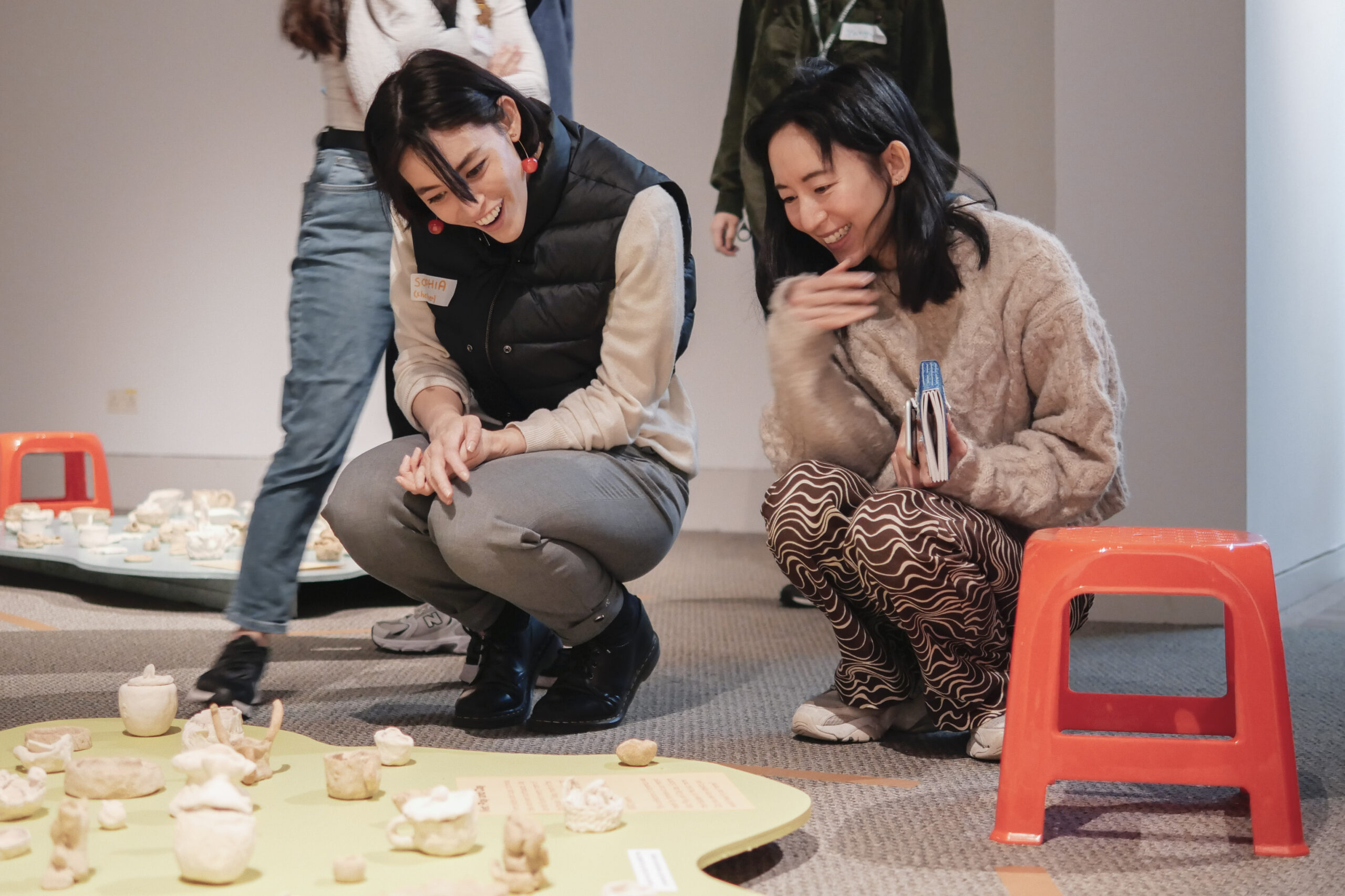 Two people sitting on the floor, smiling at an art display