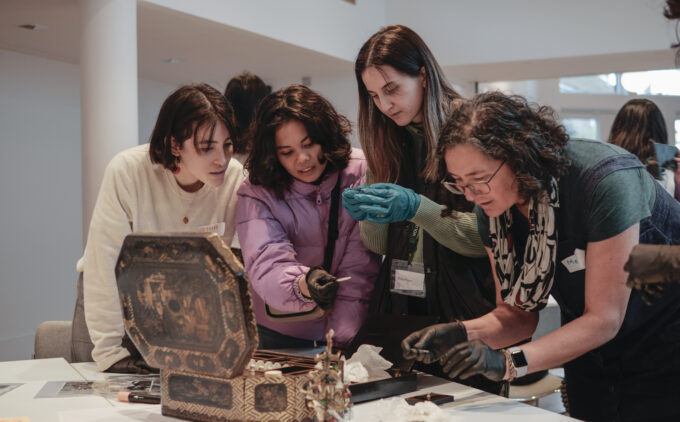 People gathered around an enameled chest, holding items with gloves