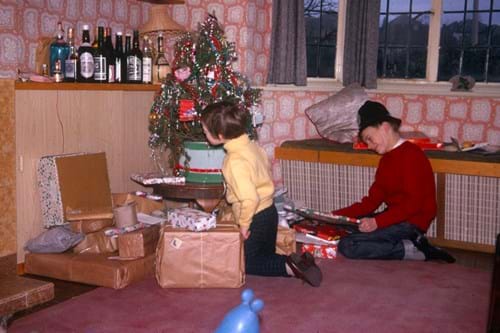 Family Christmas morning scene with children opening presents by decorated tree