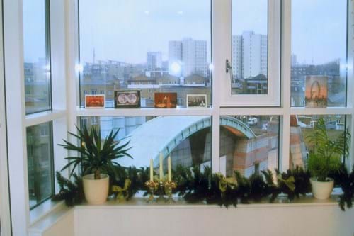 Large windows overlooking city skyline with Christmas decorations and potted plants on a window ledge