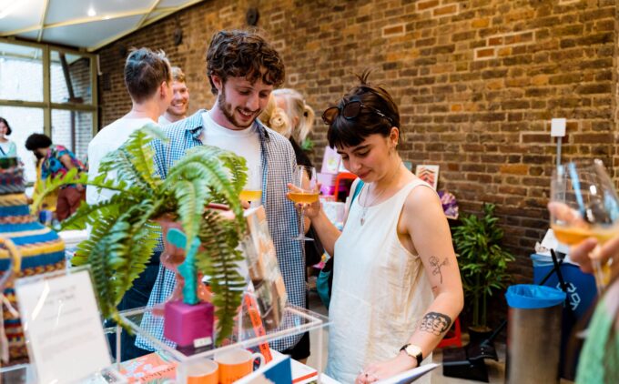 Two people holding drinks and browsing items at a shop.