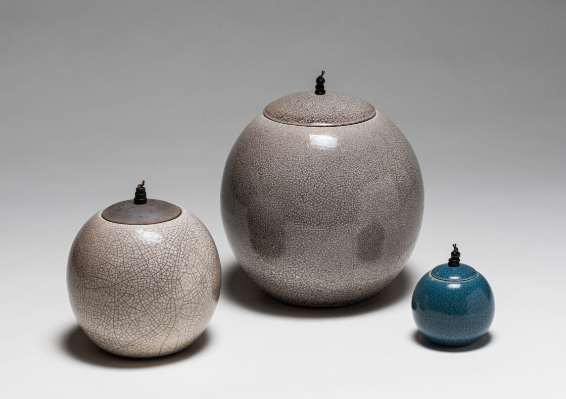 Three circular ceramic lidded jars of varying sizes with crackle glazes.