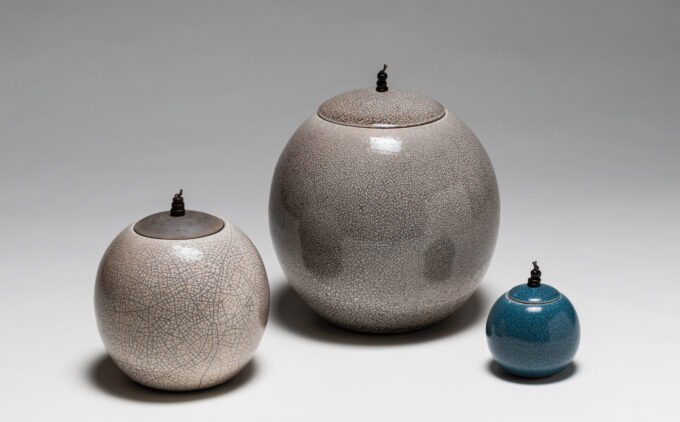 Three circular ceramic lidded jars of varying sizes with crackle glazes.