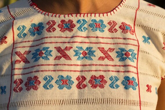 Close-up of embroidered textile with geometric blue and red cross-stitch patterns