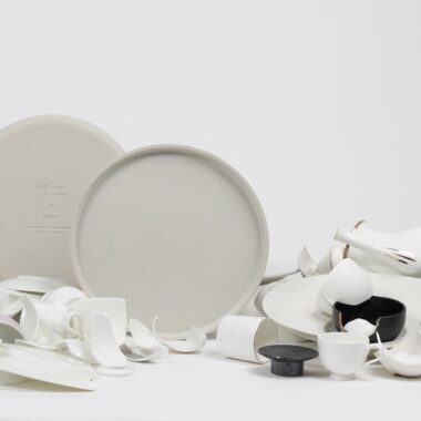 White ceramic plates and scattered paper ribbons on white surface