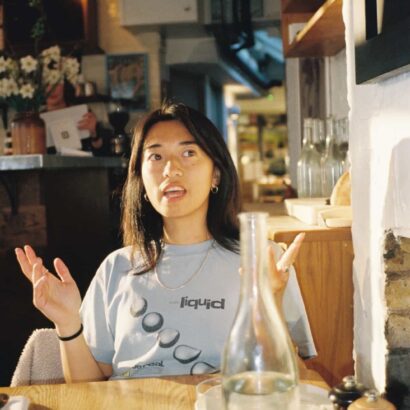 A woman sits at a cafe table, talking.